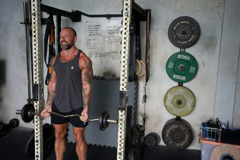 Coach Boltz training biceps with a barbell in the gym