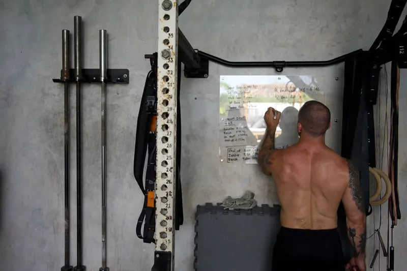 Coach Boltz hand-writing a client's weekly program on the gym whiteboard